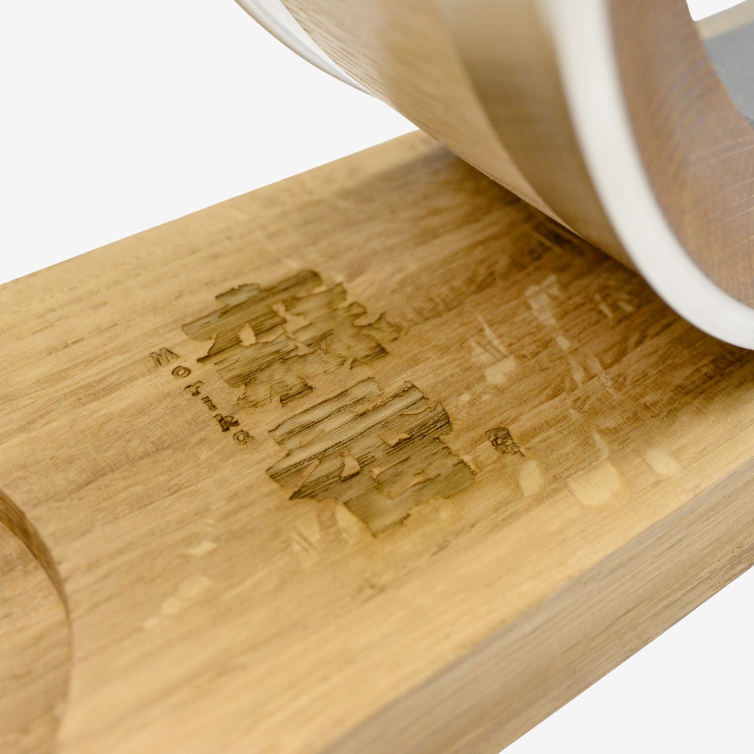 A detailed view of the laser-engraved 'Morika' brand logo on the solid oak display stand for the Visual Aging Oak Barrel Decanter.
