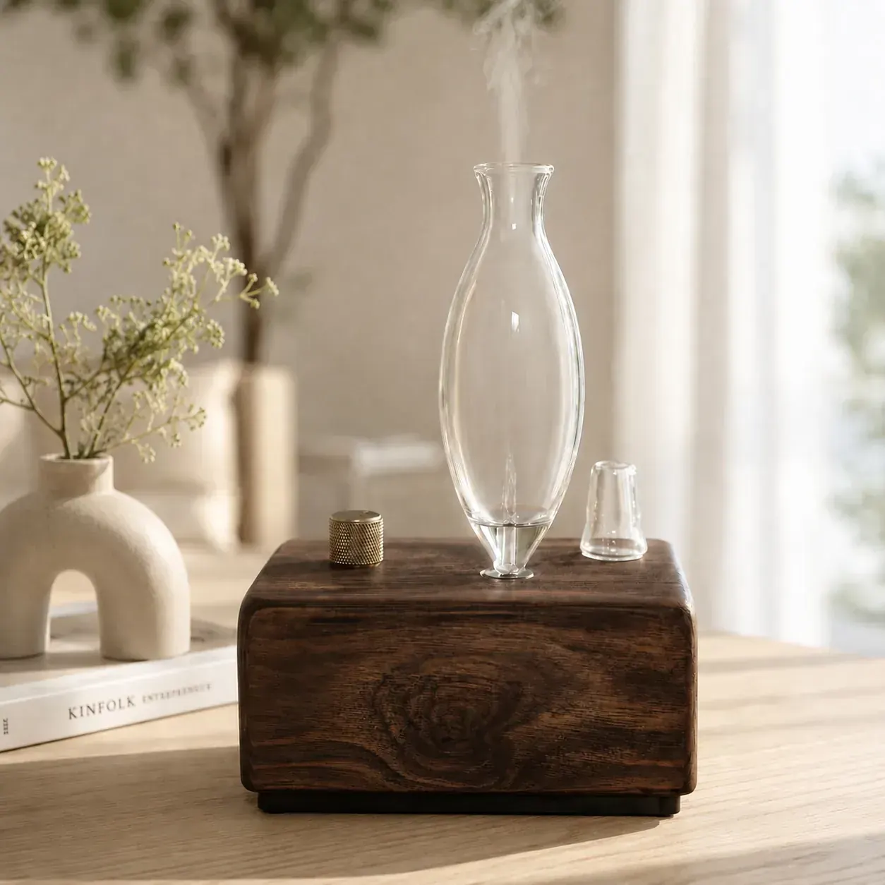 Dark hardwood dual-fluid aroma diffuser with tall glass vessel releasing aromatic mist