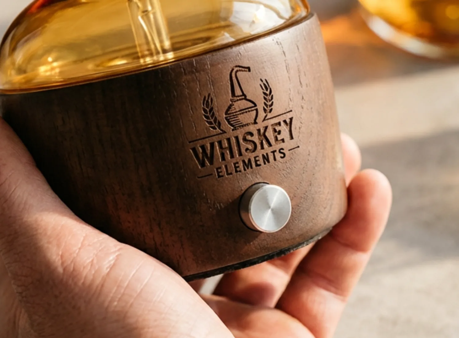 Hand holding a dark wood dual-fluid aroma diffuser base with a laser-engraved brand logo for one-unit ODM review