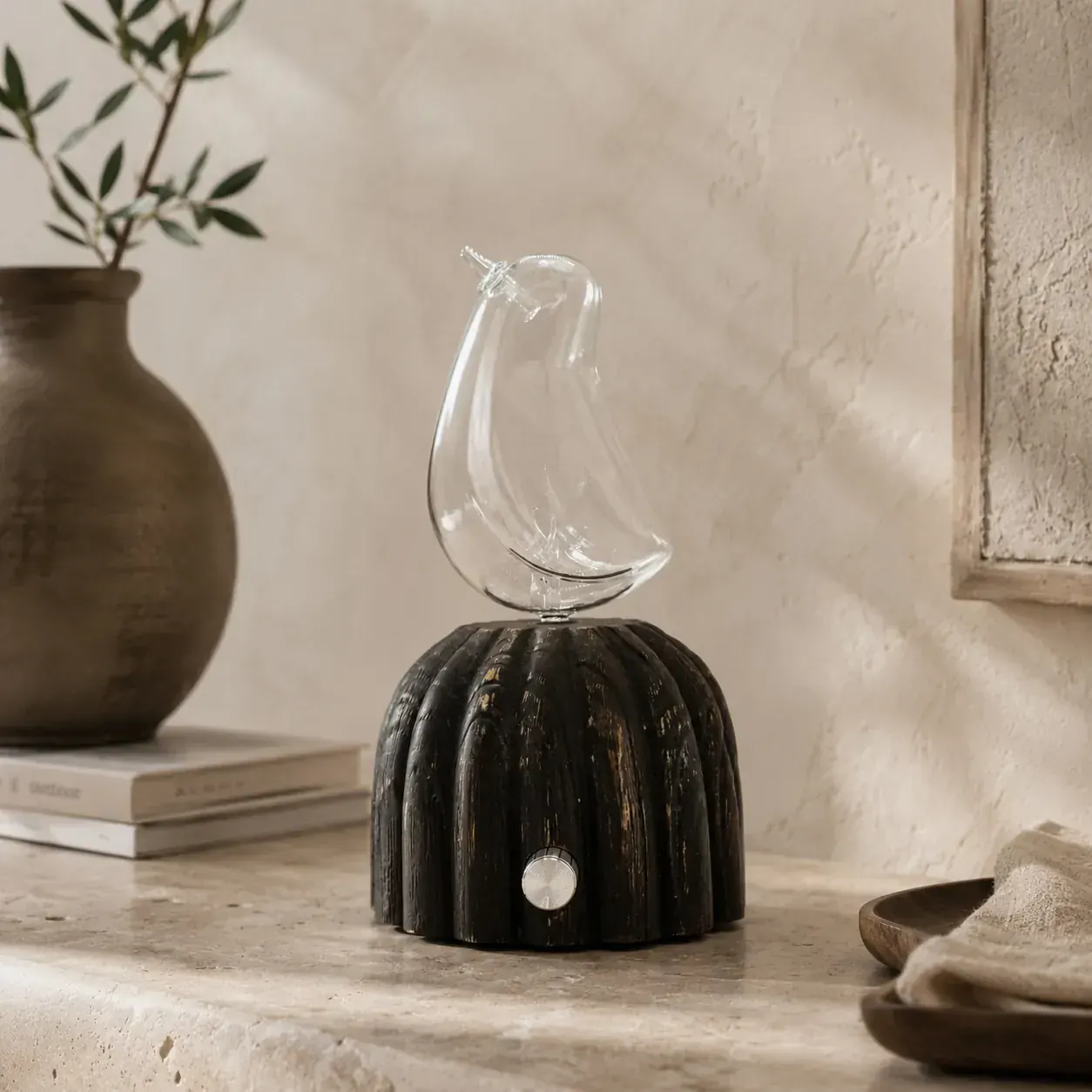 Sculptural glass dual-fluid aroma diffuser on a fluted dark wood base